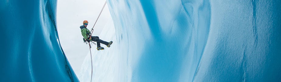 Ice climber rappelling in cave