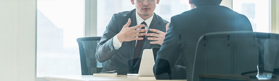 Business professionals engage in discussion in conference room with glass walls