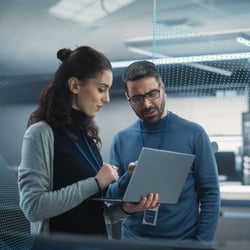Two individuals analyzing data on a laptop