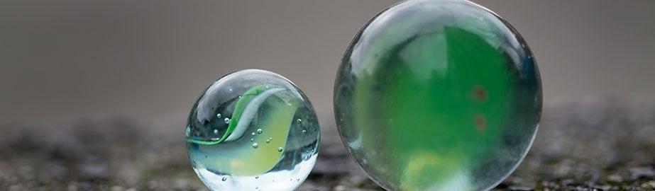 Two green marbles on concrete surface