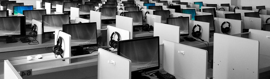 Empty gray call center with abandoned computer monitors and headsets