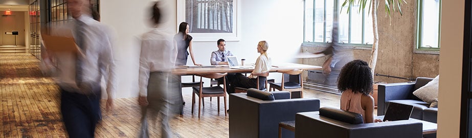 Professionals walking through office space as colleagues meet