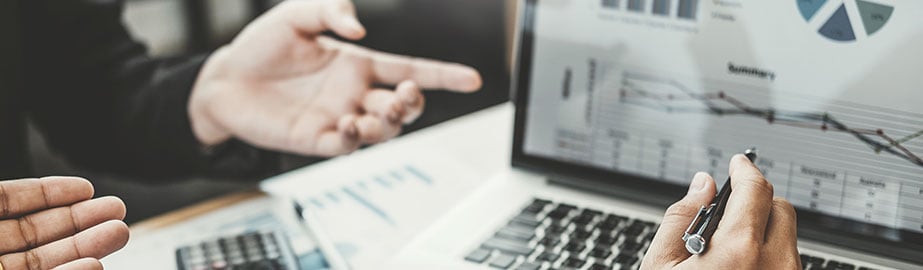 Colleagues look at graphs together on laptop screen