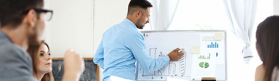 Group of professionals meet and engage data on whiteboard.