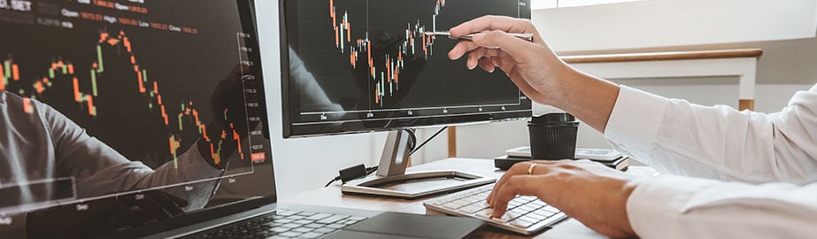 Hands point to computer monitor with graphs