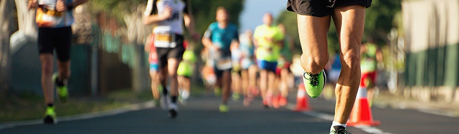 Runner taking lead in race on road with many other contestants following