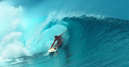 Surfer riding blue wave