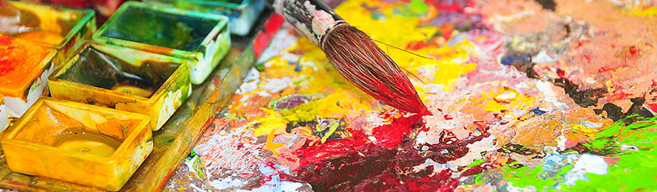 Paintbrush and brightly colored wet paints on artist's canvas